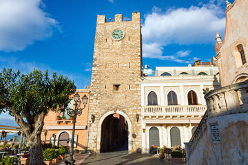 Historic stone clock tower located on Piazza IX Aprile in Taormina, Sicily, Italy. Popular tourist attraction in Taormina with scenic views, traditional buildings and Mediterranean architecture.
