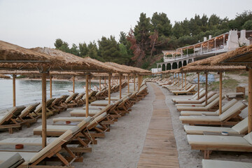 Empty beach with straw umbrellas and wooden sunbeds	