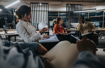 A group of diverse coworkers is actively collaborating in a modern office setting. They are seated...