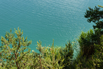 turquoise water lake surrounded by pine trees, top view.It's a beautiful summer day.background, a place to copy
