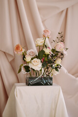 Elegant floral compositions of roses in soft pink and cream tones are placed on white-draped pedestals in a studio setting. Ideal for wedding planning, floral design, or romantic decor. 