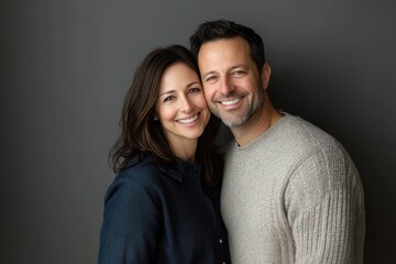 Obraz premium A happy, attractive couple is seen smiling closely in front of a gray backdrop, exuding warmth and a sense of connection.