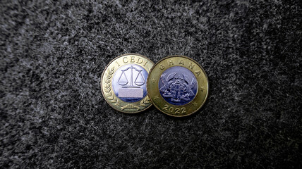Close up of 1 Ghanaian cedi coin isolated on black gray woolly fabric carpet texture background 