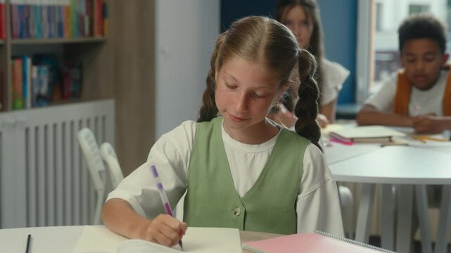 Smart girl kid child schoolgirl pupil writing task copybook at desk classwork Caucasian teen student studying in school education lesson prepare exam cognition learning teenager daughter study academy