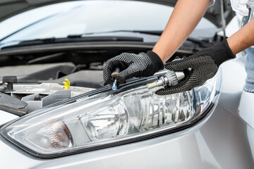  A man is fixing a car with change light bulb