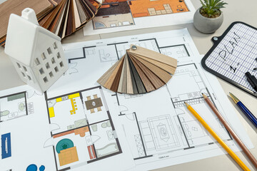 white mini house model with house blueprint on table with the drawings accessories