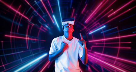 Professional male gamer with VR glasses pointing and playing game with glowing neon light. Excited...