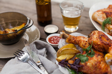 Top-down view of pub food: baked chicken drumsticks, rustic fries, sliced pickles, sauces, and beer. Cozy and casual atmosphere. Perfect for menus, blogs, or food delivery visuals