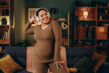 Positive plus size female enjoys energetic music singing favourite song at home