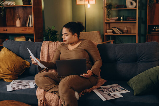 African American woman looks at clothes sketches holding laptop on laps