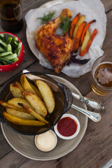 Top-down view of pub food: baked chicken drumsticks, rustic fries, sliced pickles, sauces, and beer. Cozy and casual atmosphere. Perfect for menus, blogs, or food delivery visuals