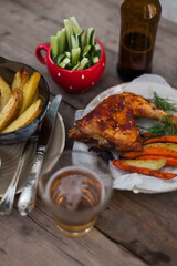 Top-down view of pub food: baked chicken drumsticks, rustic fries, sliced pickles, sauces, and beer. Cozy and casual atmosphere. Perfect for menus, blogs, or food delivery visuals
