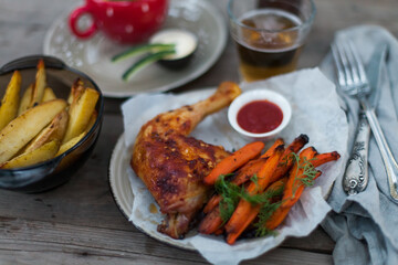 Top-down view of pub food: baked chicken drumsticks, rustic fries, sliced pickles, sauces, and beer. Cozy and casual atmosphere. Perfect for menus, blogs, or food delivery visuals