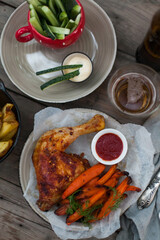 Top-down view of pub food: baked chicken drumsticks, rustic fries, sliced pickles, sauces, and beer. Cozy and casual atmosphere. Perfect for menus, blogs, or food delivery visuals