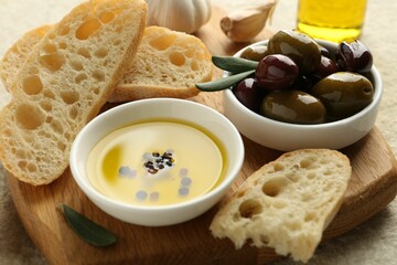 Slices of bread with oil, spices and olives on light table, closeup