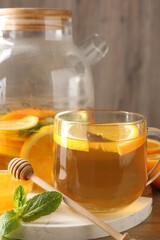 Aromatic fruit tea in glass cup, orange, lemon, honey and mint on table, closeup