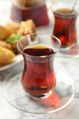 Tasty Turkish tea served with sweets on white marble table, closeup