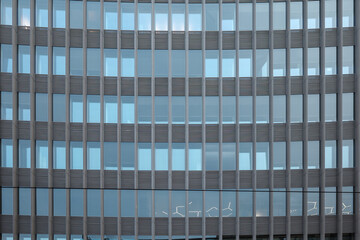 Close-up view of a modern office building featuring a vertical grid of glass panels and metal fins.