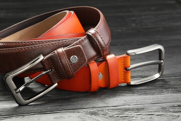 Two leather belts on wooden table, closeup