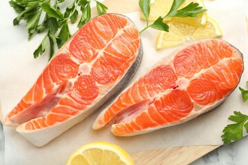 Seafood. Fresh raw salmon steaks, parsley and pieces of lemon on table, top view