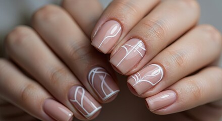 Close up of manicured hands with neutral nail polish and white geometric designs showcasing nail art elegance