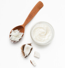 Coconut flesh in wooden spoon, bowl of coco butter and pieces of coco on white background, top view