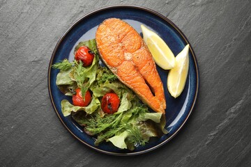 Seafood. Tasty salmon steak served with salad and lemon on black table, top view