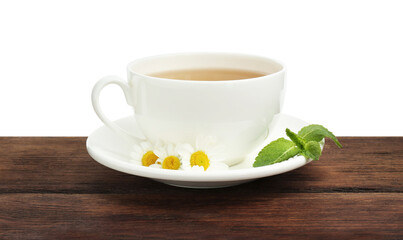 Delicious chamomile tea in cup, fresh flowers and mint on wooden table against white background