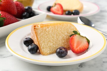 Pieces of tasty bundt cake with berries on white marble table, closeup