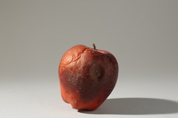 One rotten red apple on light grey background