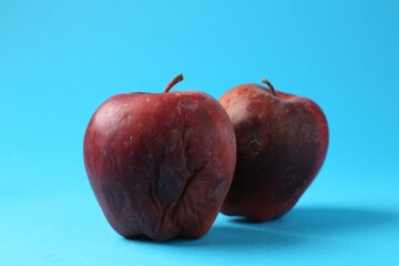 Damaged red apples on light blue background