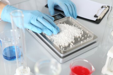 Scientist weighing sample on scales at white mirror table, closeup