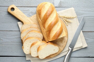 Sliced bread and knife on grey wooden table, flat lay