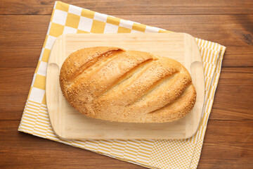 One bread loaf on wooden table, top view
