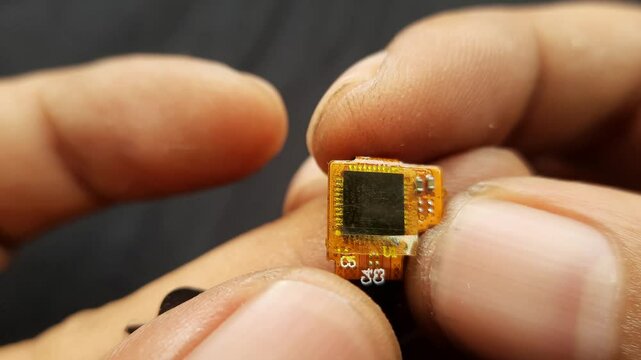 Macro Shot of Hand Holding Smartphone Flexible Display Chip