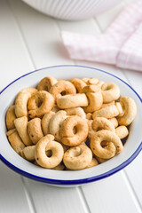 Salted crispy snack rings in bowl on kitchen table.