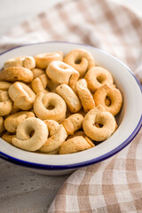 Salted crispy snack rings in bowl on kitchen table.