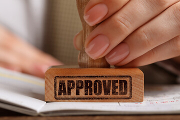 Approved. Woman stamping passport at table, closeup