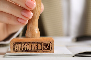 Approved. Woman stamping passport at table, closeup
