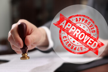 Man stamping document at table and red stamp Approved