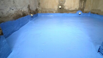 Waterproofing a bathroom floor, applying blue sealant paint