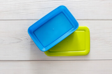 Empty plastic lunch boxes on white wood, top view. Green and blue containers