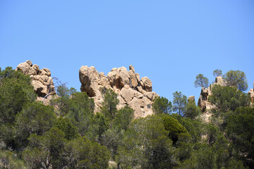 Fototapeta premium Rugged rock formations and greenery against clear blue sky