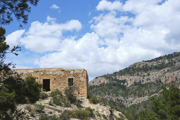 Abandoned stone house in mountainous landscape under bright blue sky
