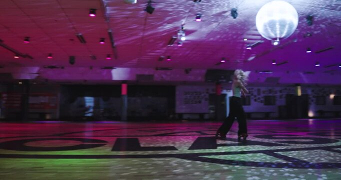 Lone, talented roller skater sliding backwards on skate floor and nearly falling backwards - steady cam movement