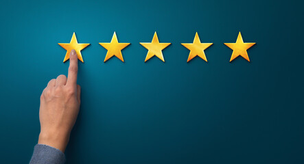 Hand of client giving a five star rating on blue background, panorama, copy space. Service rating,...