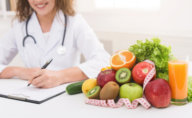Paperwork. Nutritionist writing diet plan, sitting at workplace with vegetables, free space