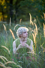 Person sitting in tall grass during golden hour in a natural setting