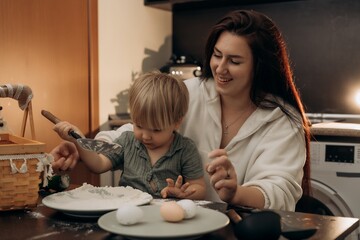 Gentle parenting moment in cozy kitchen as mom and toddler enjoy bonding over flour eggs and playful sensory experience full of laughter touch warmth connection mindful motherhood and childhood joy