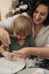 Mom gently kisses toddler while child plays with flour creating heartwarming bonding moment filled with sensory joy cozy emotion motherhood love and sweet childhood memory in kitchen light